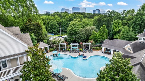 A swimming pool surrounded by trees and houses.