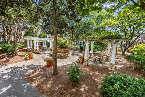 A garden with a white pergola and a circular brick structure.