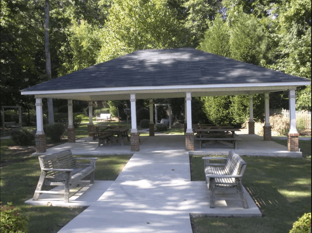 A gazebo is surrounded by benches and pillars.