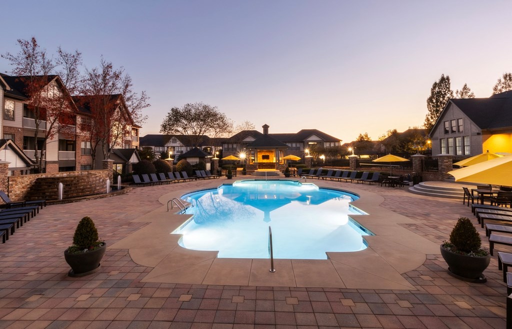 a swimming pool in a backyard at dusk at The Reserve at Sugarloaf Apartments, Duluth