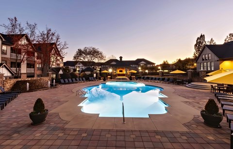 Swimming pool at dusk with lounge seating.