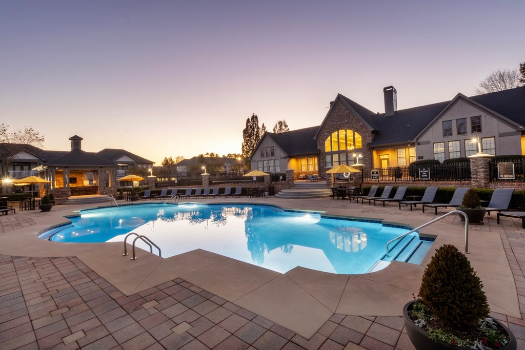 a swimming pool in front of a hotel at dusk at The Reserve at Sugarloaf Apartments, Georgia, 30097