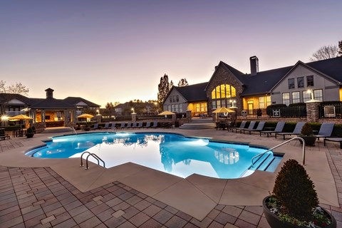 A large swimming pool in a backyard with a house in the background.