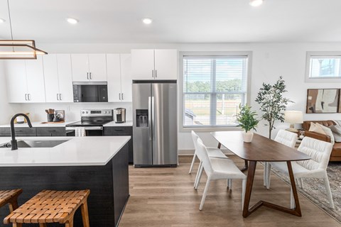 a kitchen and dining room with white cabinets and a stainless steel refrigerator