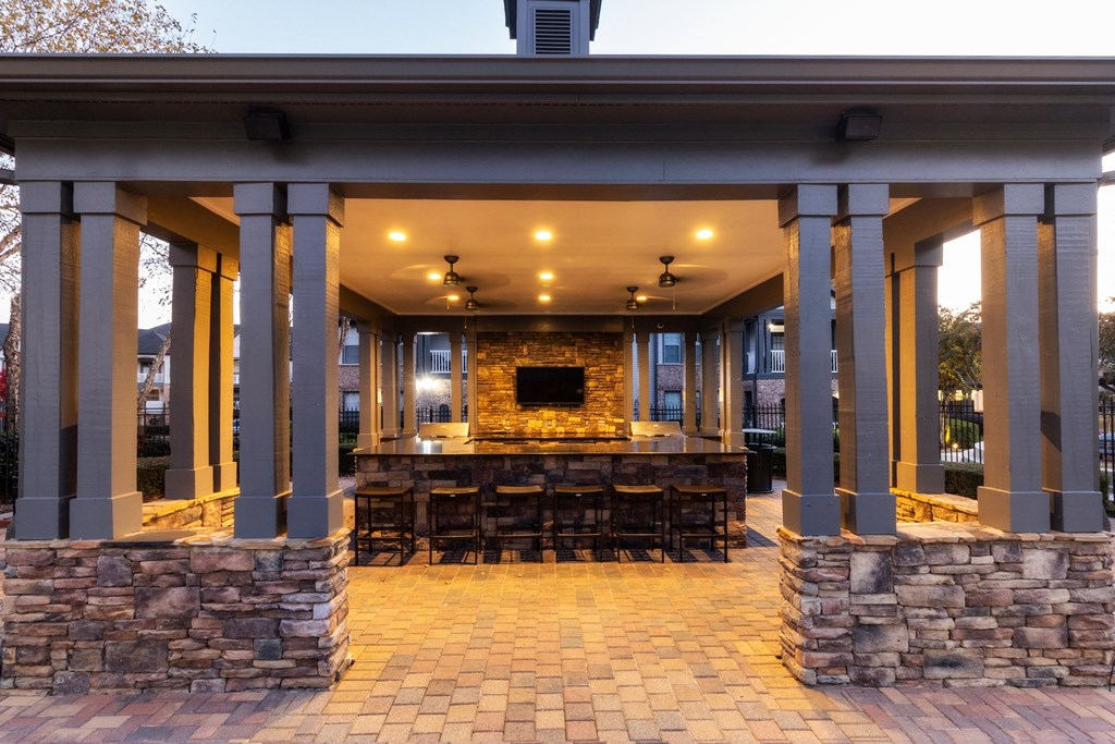 a covered patio with a bar and a fireplace at The Reserve at Sugarloaf Apartments, Duluth, Georgia