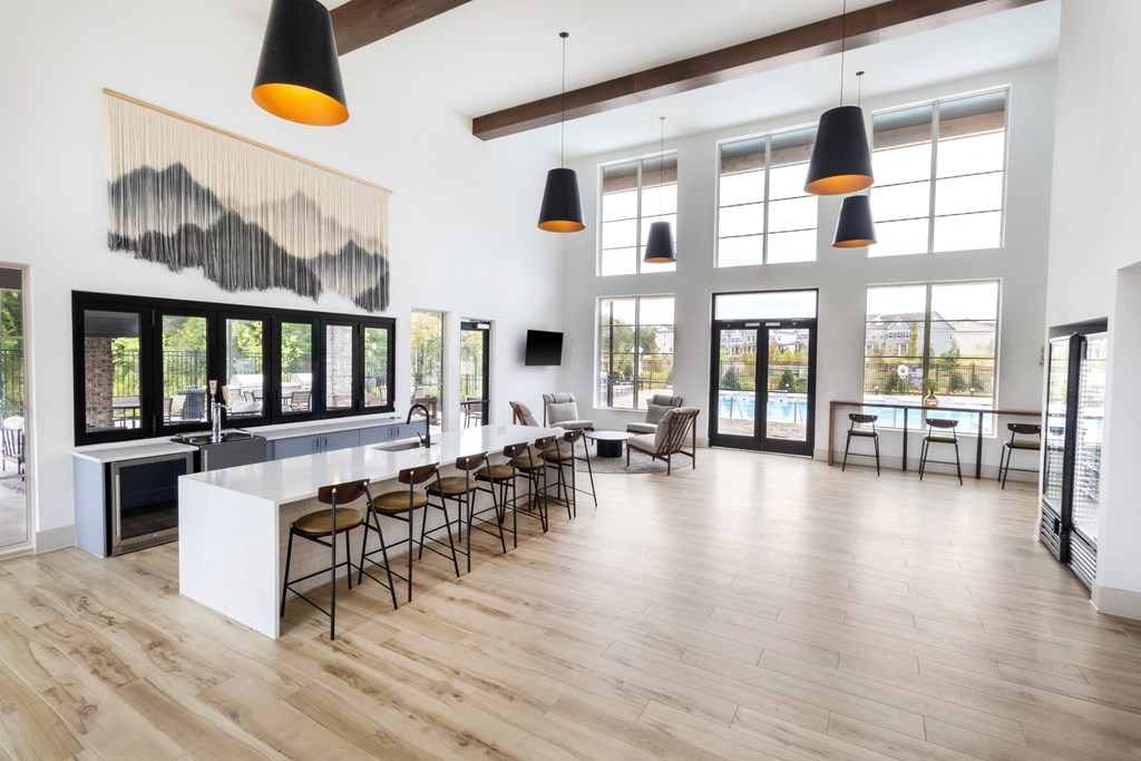 a large room with a bar and chairs in it and large windows