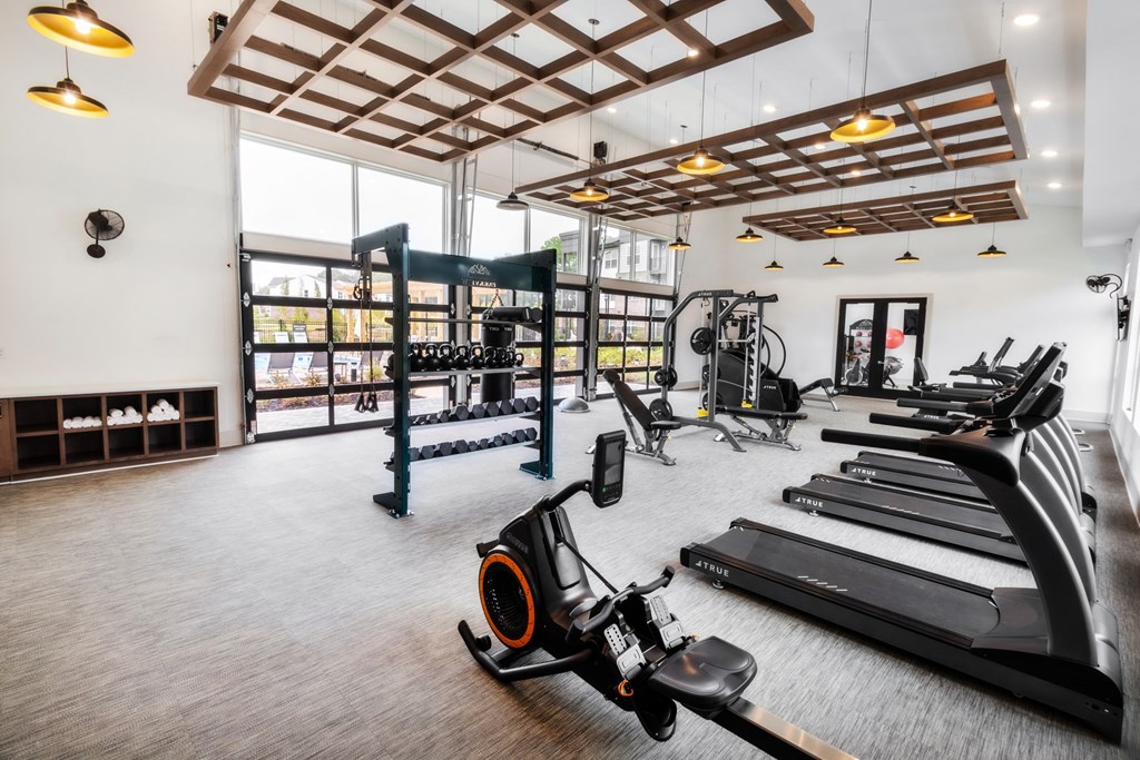 two treadmills and other exercise equipment in a gym with glass walls and windows