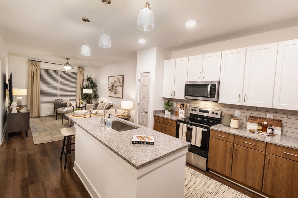 an open kitchen and living room with white cabinets and granite counter tops