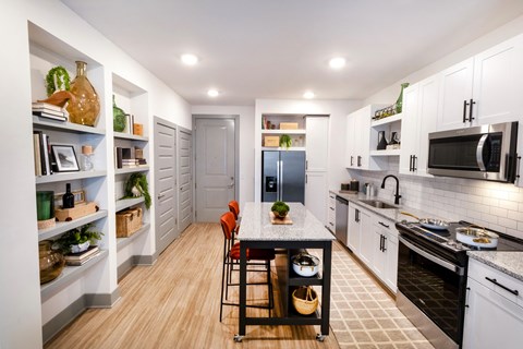 a kitchen with white cabinets and black appliances and a table with chairs