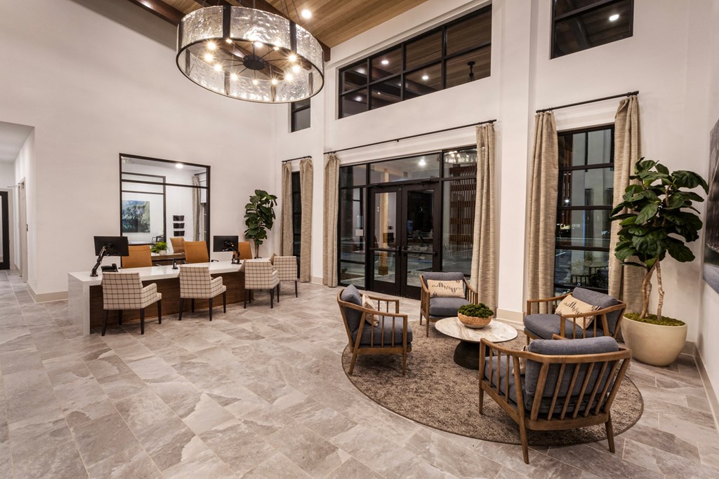 a living room with chairs and tables and windows