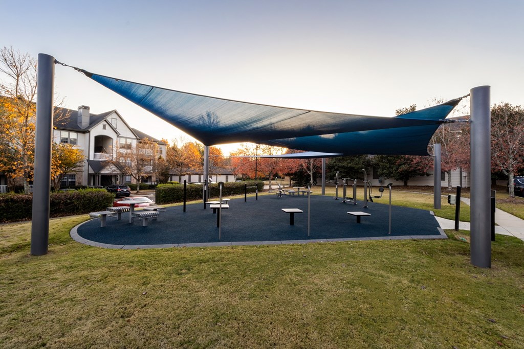a park with picnic tables and a blue canopy at The Reserve at Sugarloaf Apartments, Duluth, Georgia