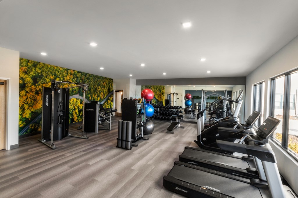 a gym with treadmills and other exercise equipment and a wall of green plants