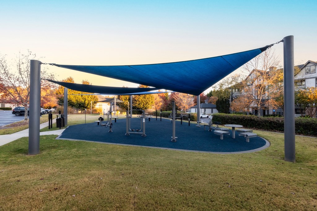 a blue canopy over a playground in a park at The Reserve at Sugarloaf Apartments, Duluth