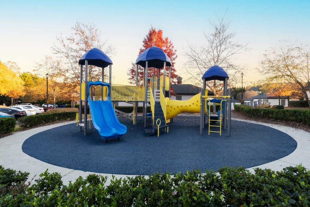 a playground with a yellow and blue swing set at The Reserve at Sugarloaf Apartments, Georgia