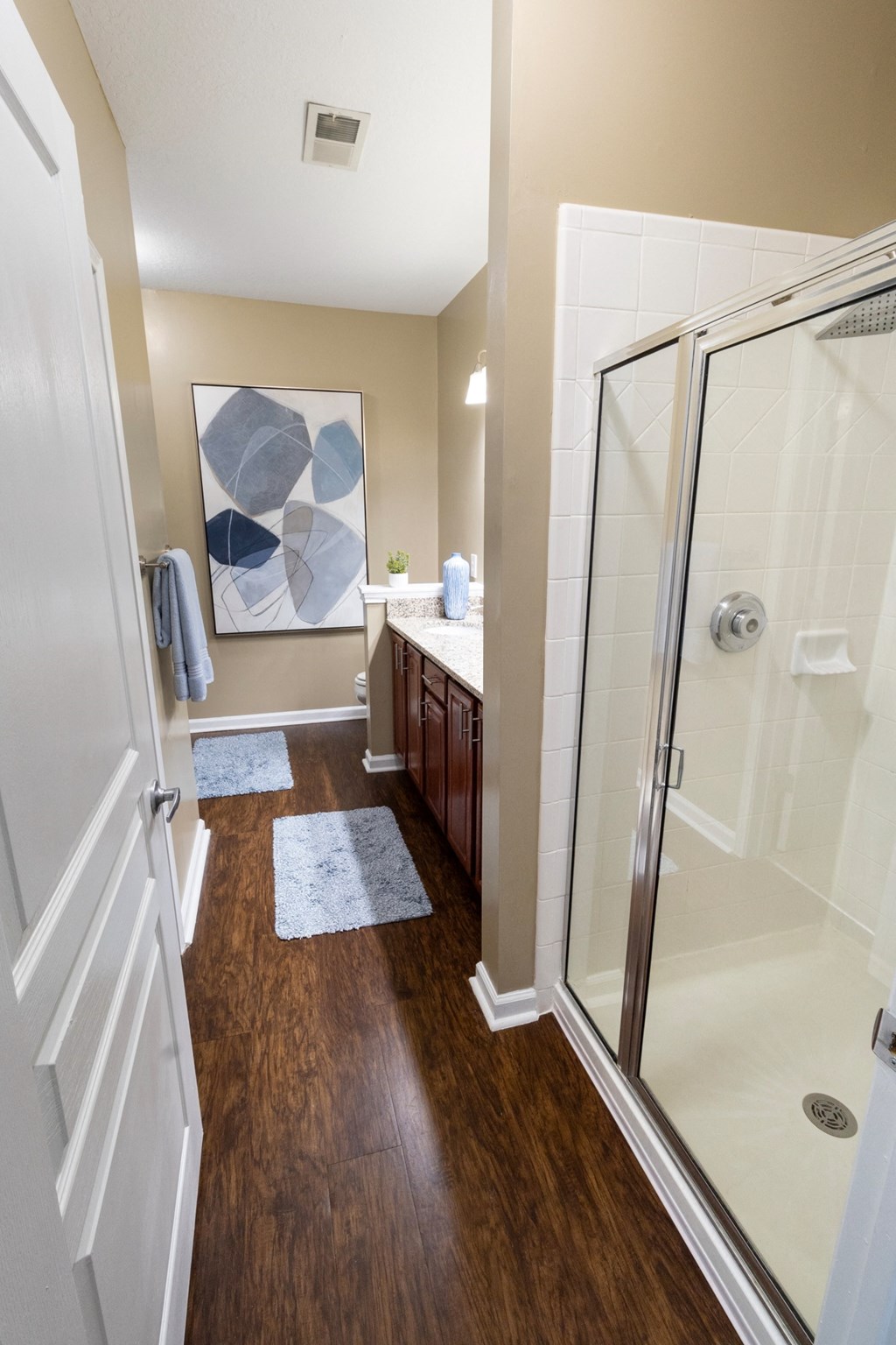 a bathroom with a shower and a sink and a mirror at The Reserve at Sugarloaf Apartments, Duluth, Georgia