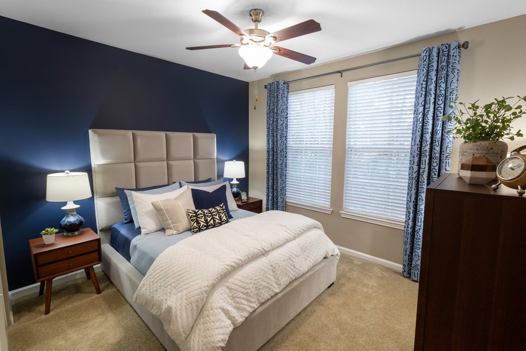 a bedroom with a large bed and a ceiling fan at The Reserve at Sugarloaf Apartments, Duluth, GA