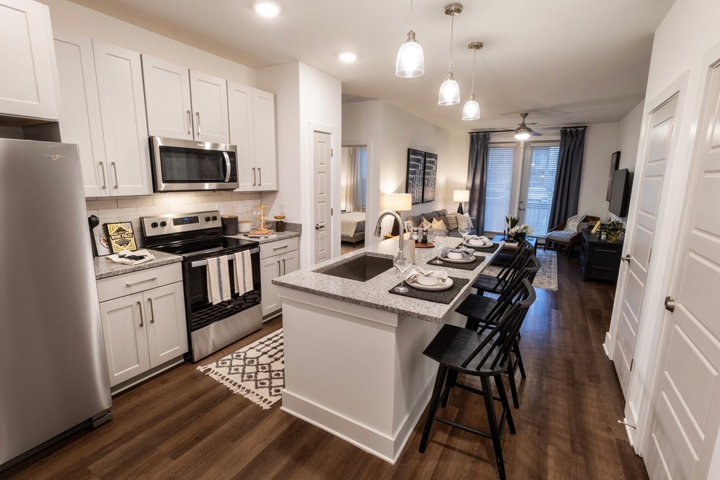an open kitchen and living room with a dining area and a kitchen island with chairs