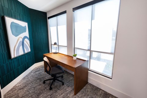 a home office with a desk and three windows