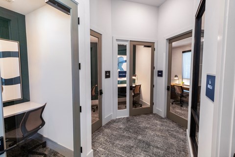 a corridor with several doors to different rooms and desks