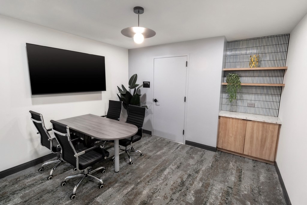 an empty conference room with a table and chairs and a tv