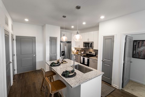 a kitchen with an island with granite counter top and a sink