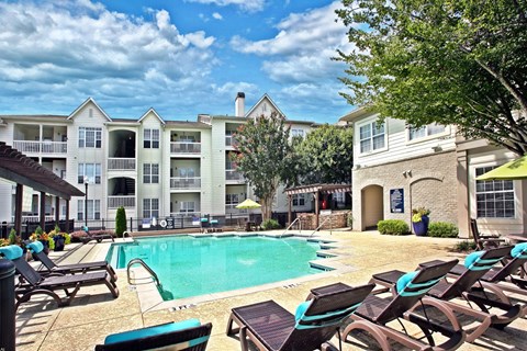 A sunny day at the poolside of a resort with lounge chairs and a swimming pool.