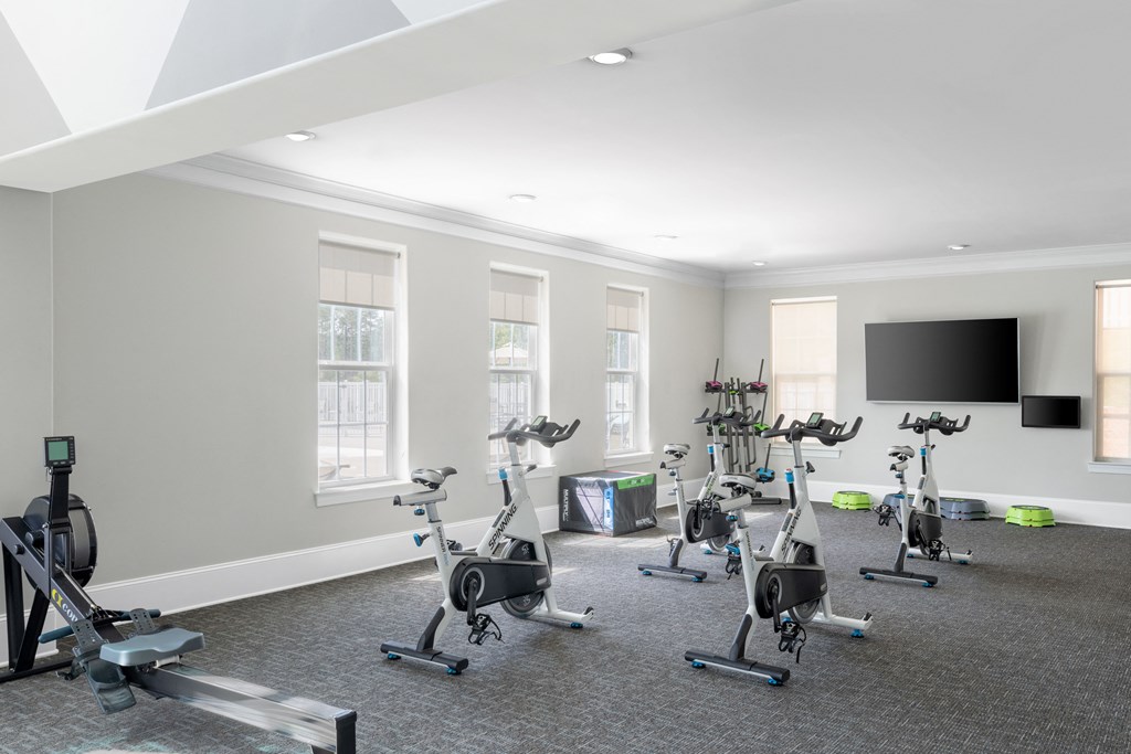 a room filled with exercise bikes and a flat screen tv