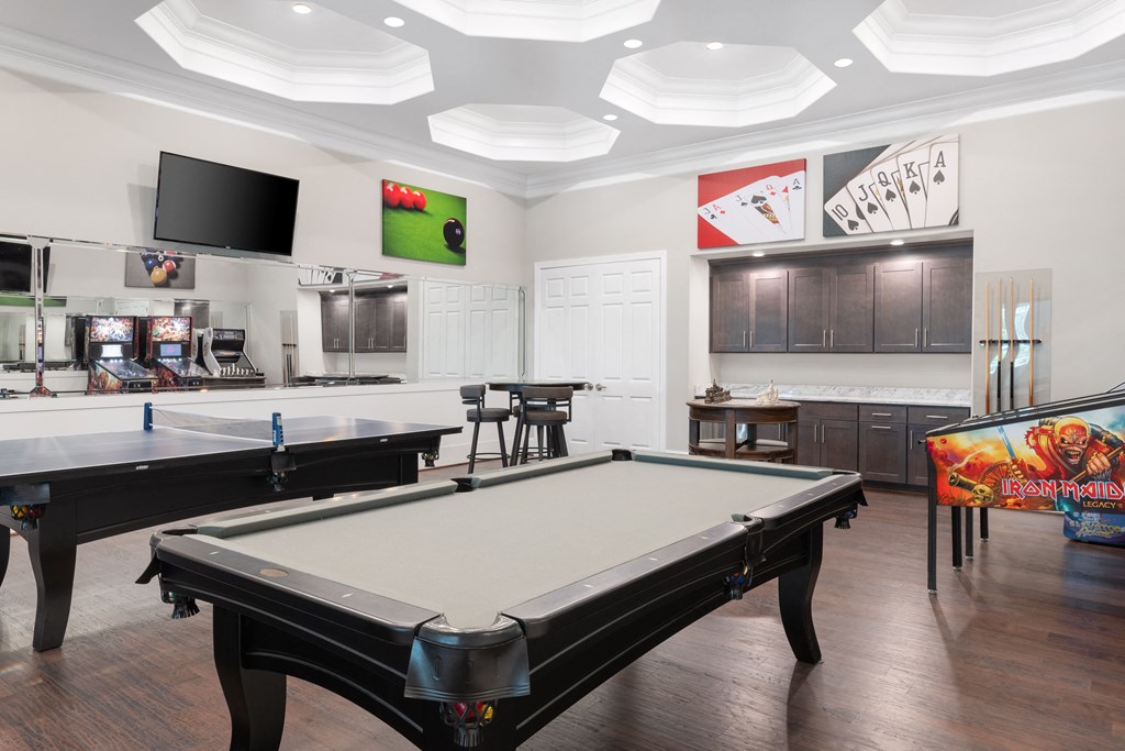 a recreation room with two pool tables and a flat screen tv
