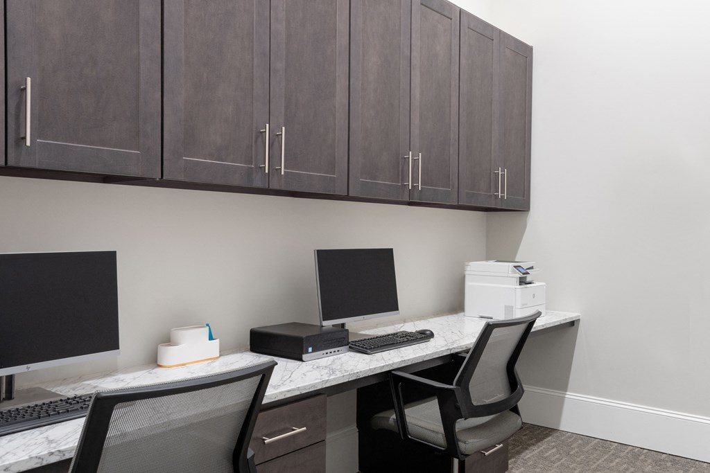 a desk with two computer monitors and a printer