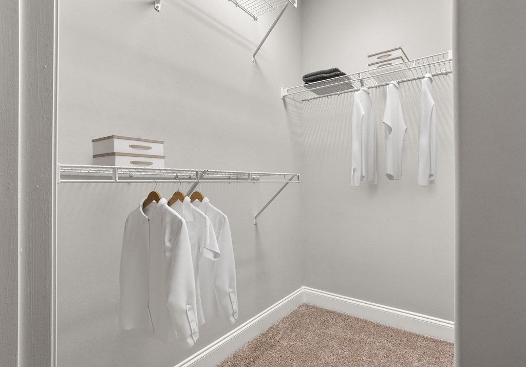 a spacious walk in closet with white clothes