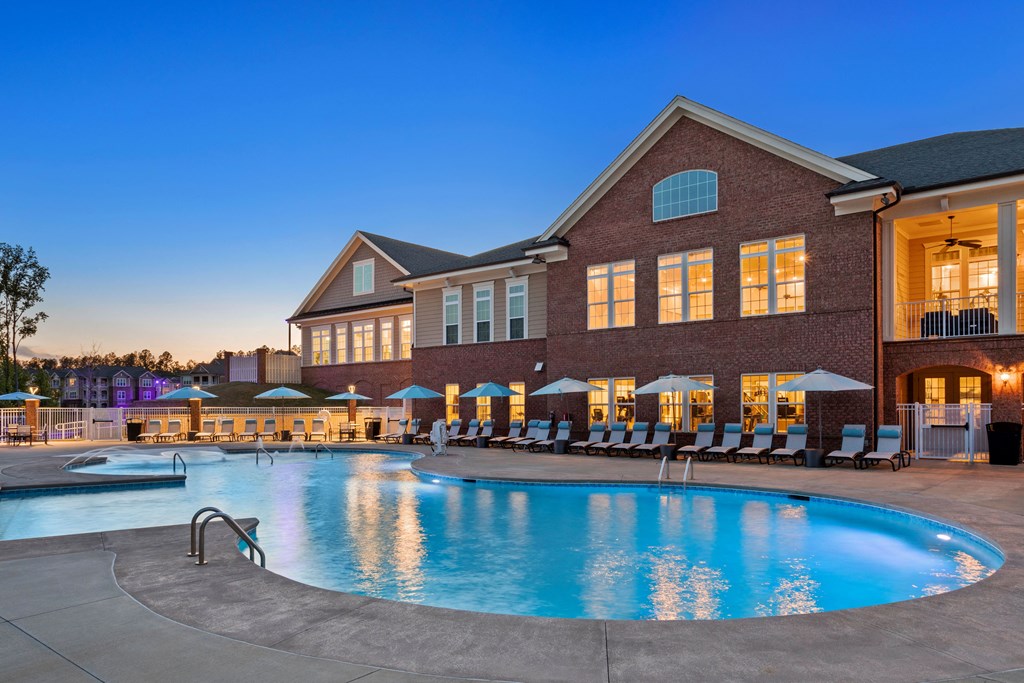 a swimming pool with lounge chairs and umbrellas in front of a brick building