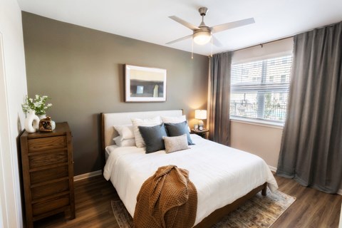 a bedroom with a large white bed and a ceiling fan at Woodlands Creekside Apartments, Georgia