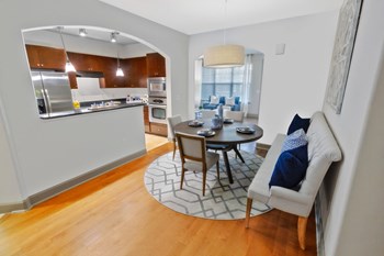 a dining area with a table and chairs and a kitchen in the background - Photo Gallery 17