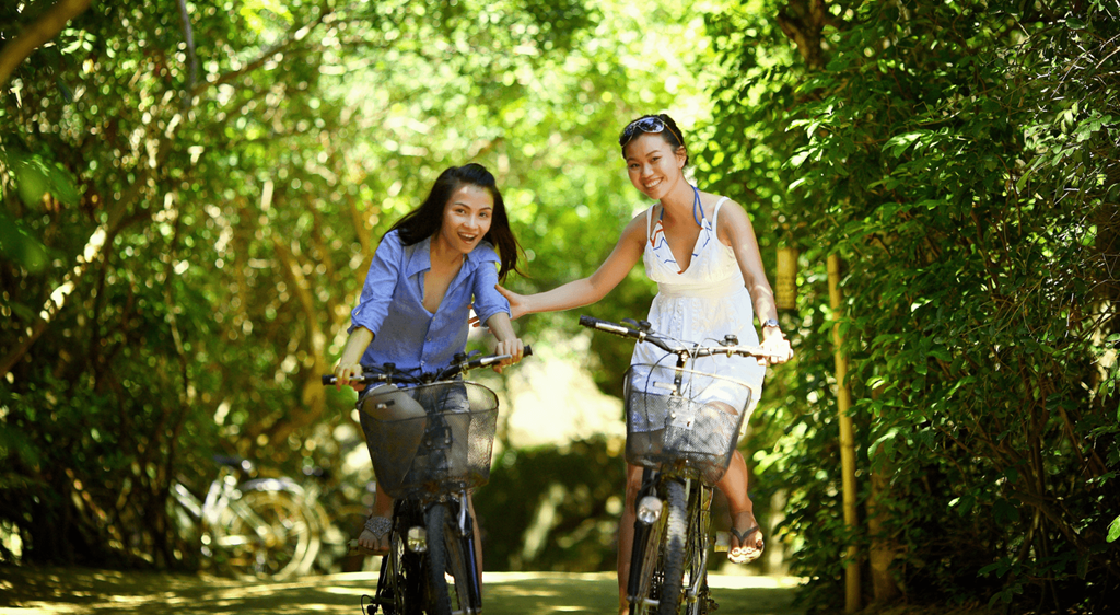 two women riding bikes down a path
