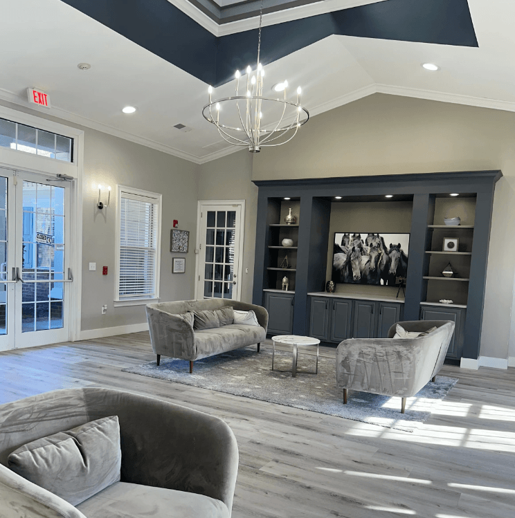 Clubhouse with a grey couch and a chandelier. at The Dawson Cartersville in Cartersville, GA 30191