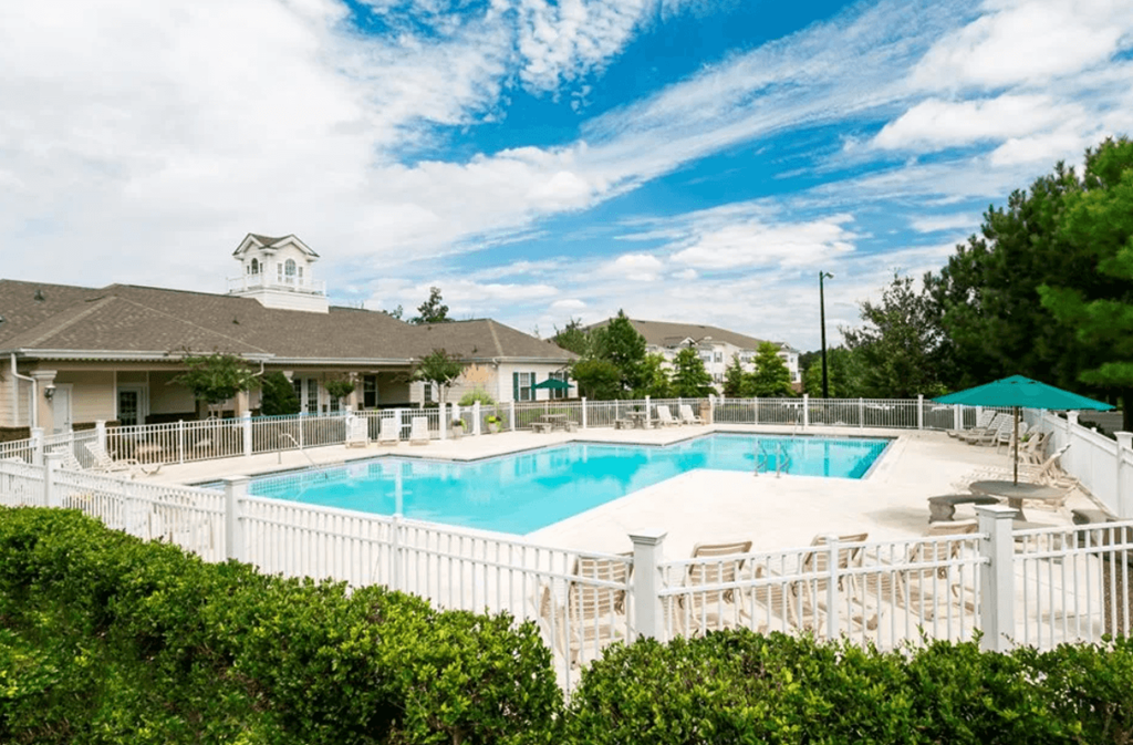 A pool surrounded by a white fence and green bushes. at The Dawson Cartersville in Cartersville, GA 30191