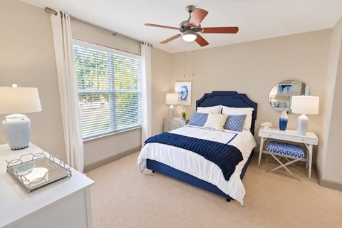 A bedroom with a bed, nightstand, and window.