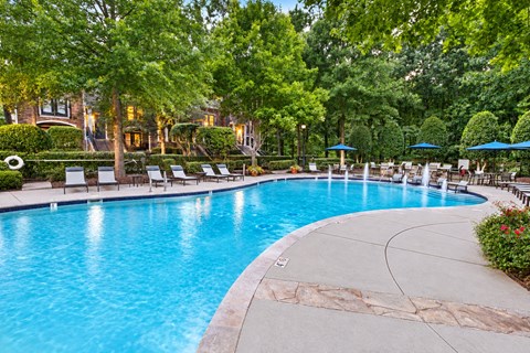 A large swimming pool surrounded by trees and lounge chairs.