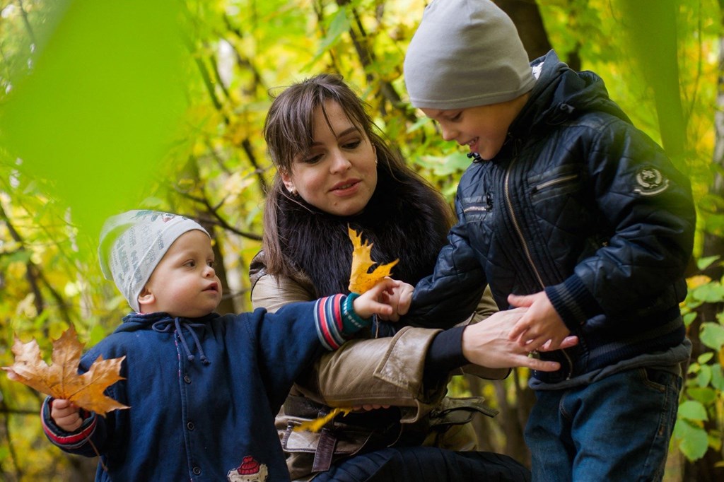 a family playing with leaves in the autumn forest