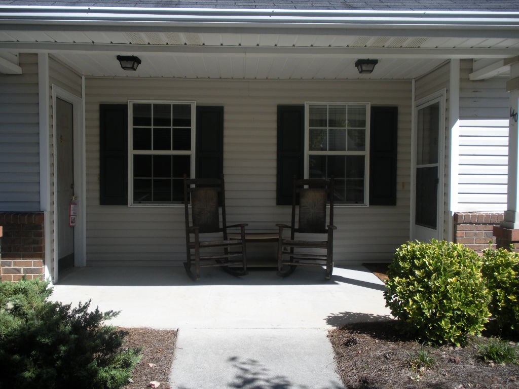A white house with a porch and two rocking chairs.
