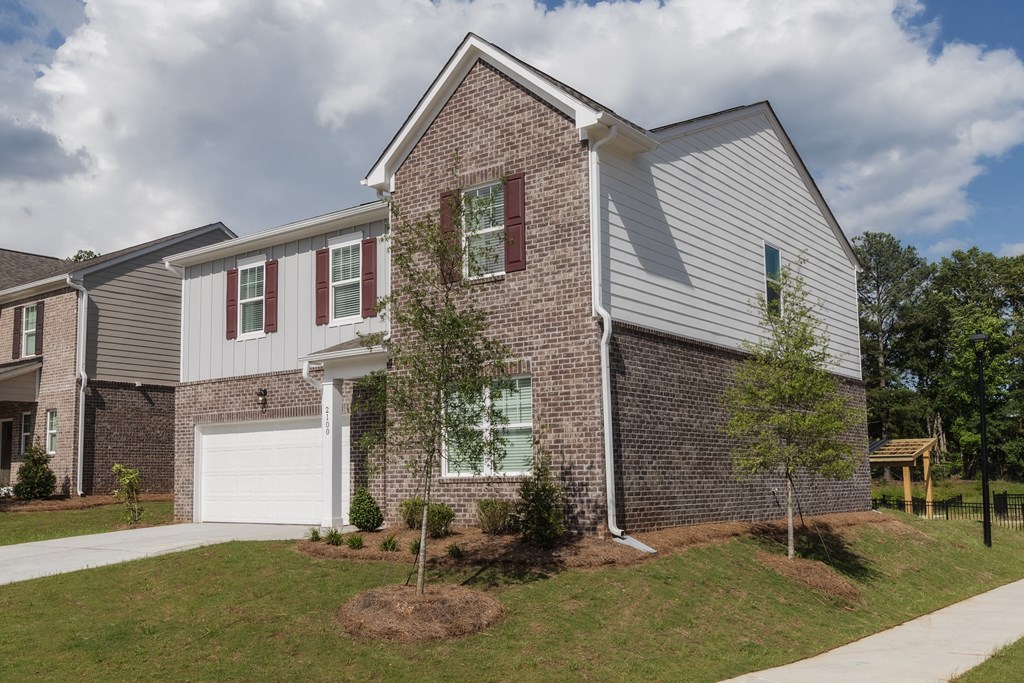 a brick house with white siding and a white garage door