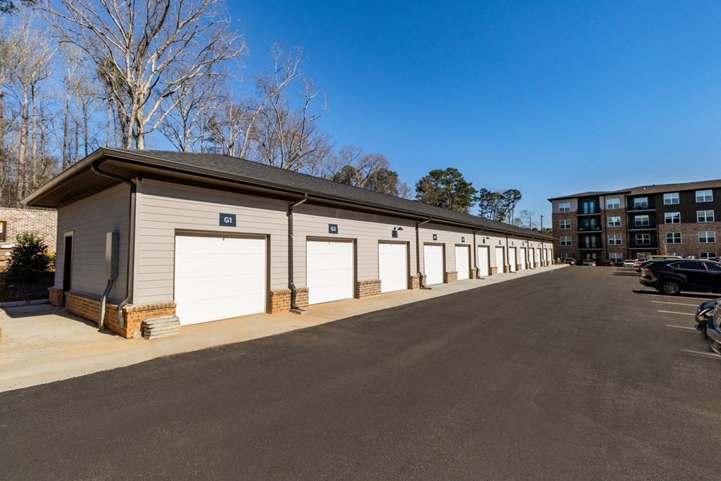 a long building with white garage doors and a parking lot