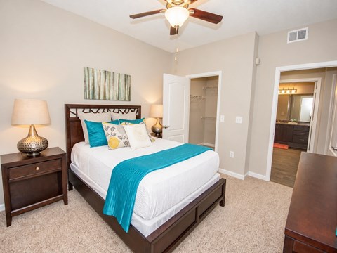 A bedroom with a bed, nightstand, and a ceiling fan.