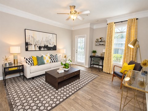 A living room with a white couch, a coffee table, and a painting on the wall.