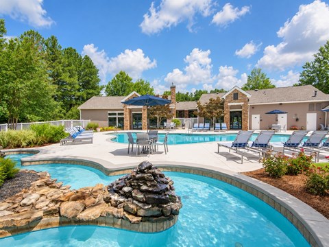 A large outdoor swimming pool with a rock feature in the middle.