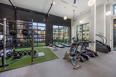 A gym with a variety of equipment including treadmills, weights, and exercise machines.