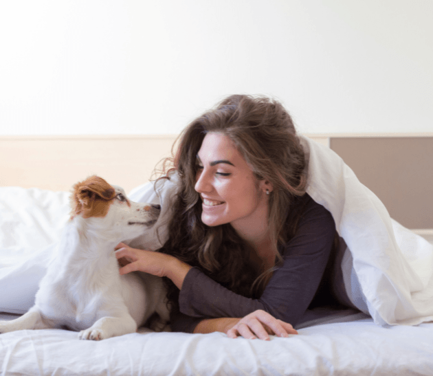 a woman laying on a bed with her dog