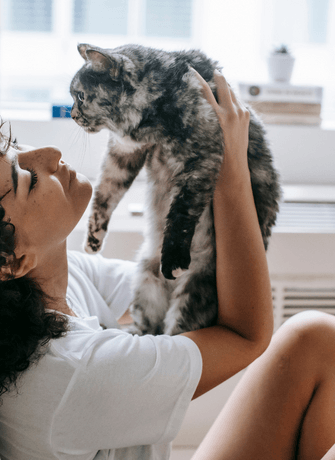 a woman is holding a cat on her head