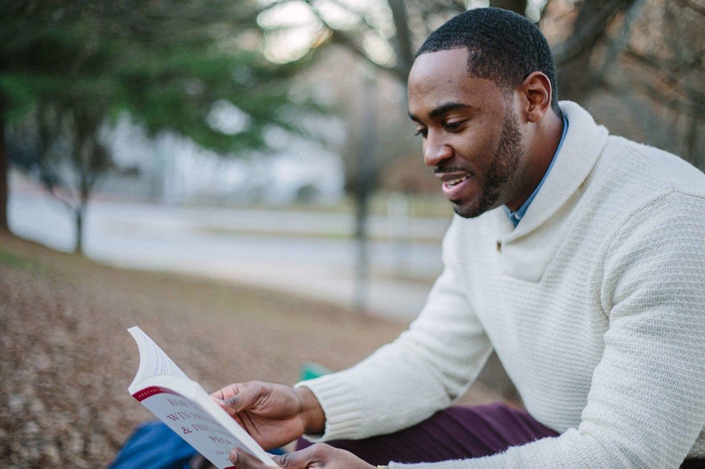 a man sitting in a park reading a book
