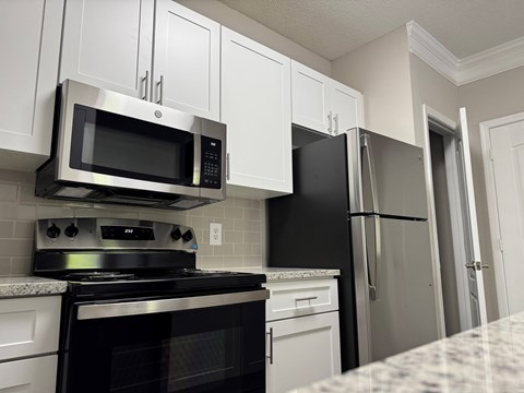 A kitchen with a black stove top oven and a black microwave above it.